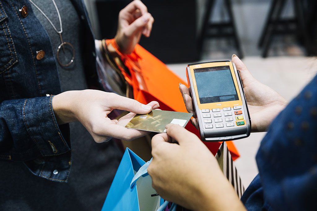 Comerciante e consumidor efetuam pagamento em cartão de crédito em loja